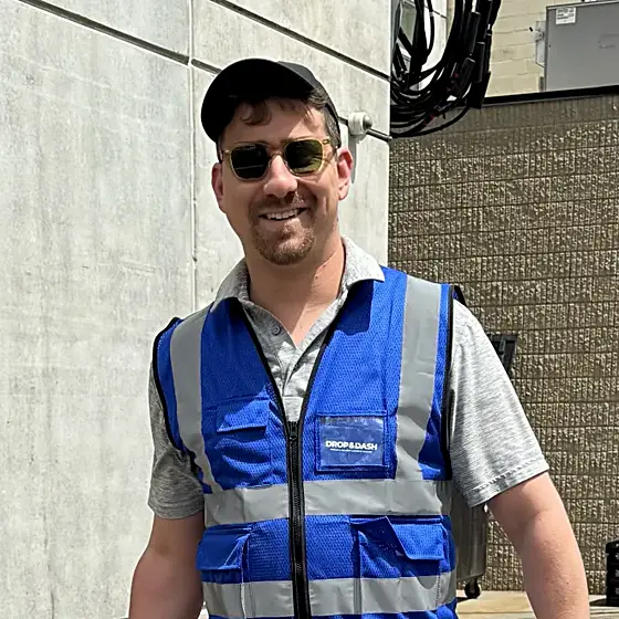 A Drop & Dash driver carrying two blue delivery bags